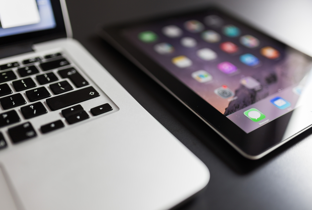 black iPad beside a mac book