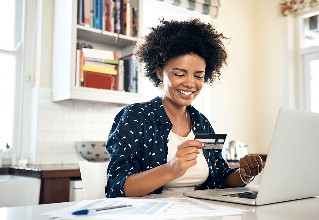 Woman using her debit card while on a laptop computer.