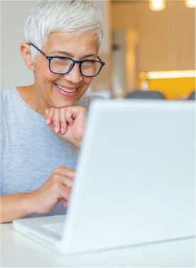 Elderly adult on a laptop computer smiling.