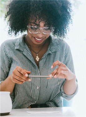 Woman smiling while using her smart phone to deposit a check.